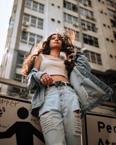 a woman standing in front of a tall building with her hair blowing in the wind