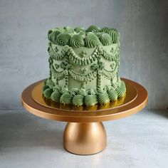 a green cake sitting on top of a gold plate