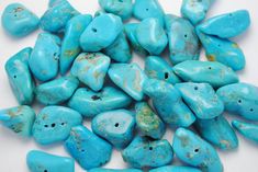 turquoise colored stones are scattered on a white surface