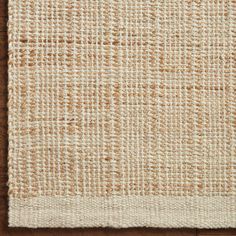 an area rug with brown and white squares on the floor, in front of a wooden surface