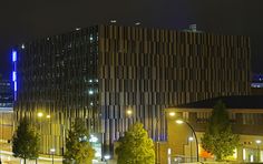 the building is lit up at night with street lights and trees in front of it