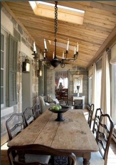 a dining room table with chairs and a chandelier hanging from it's ceiling