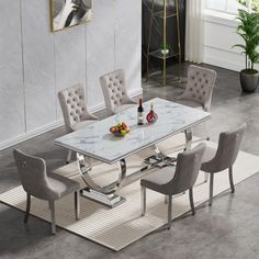 a dining room table with chairs and a vase filled with fruit on the top, in front of a white rug