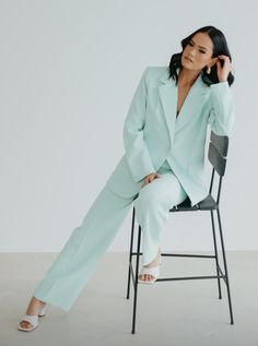 a woman sitting on top of a chair wearing a green suit