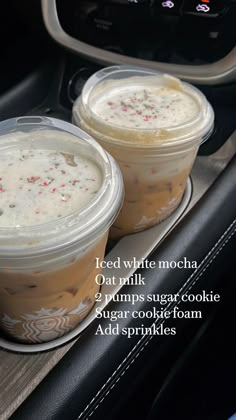 two plastic cups filled with ice cream sitting on top of a car dash board in front of an oven