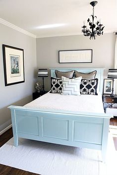 a bedroom with a bed, chandelier and pictures on the wall above it