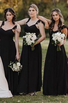 a group of women standing next to each other wearing black dresses and holding bouquets