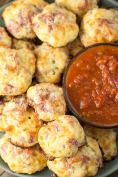 a green plate topped with mini pizzas and dipping sauce on top of it next to a bowl of ketchup