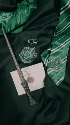 a harry potter tie, wand and keychain on a black satin bed sheet