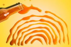 a hand holding a bottle with liquid coming out of it and an orange fingerprint