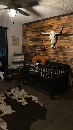 a baby's room with a cow skull mounted on the wall and other decor