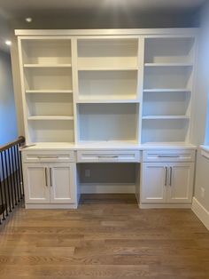 an empty room with white bookcases and wooden floors