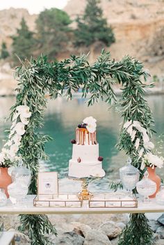 a table topped with a white cake and greenery