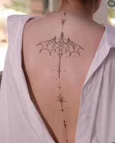 the back of a woman's neck with an intricate tattoo design on her lower back