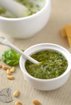 a bowl of pesto next to two bowls of cheese