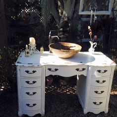 an old dresser with a bowl on top and other items sitting on the drawers in front of it