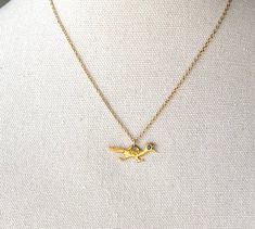 a gold bird necklace on a mannequin neck