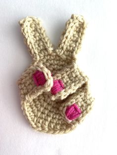 a crocheted bunny shaped object with pink eyes and ears sitting on top of a white surface