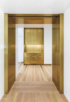 an empty room with wooden floors and gold cabinets