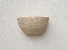 a white wall with a cement bowl on it