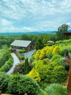 a house in the middle of a lush green field with lots of trees and bushes