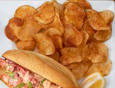 a plate with potato chips and a sandwich on it next to a pile of fried potatoes