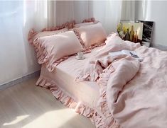 a bed with pink ruffled sheets and pillows