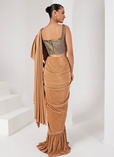 This elegant Gold Pre-Draped Lycra Saree Set, crafted from a luxurious blend of lycra and crepe, exudes timeless sophistication. The fluid draping of the gold saree, enhanced by the rich texture of the fabrics, makes it a standout choice for any special occasion. Paired with a striking grey blouse, intricately hand-embellished to add a touch of glamour, this ensemble is perfect for festive celebrations or sangeet ceremonies. Composition : Blouse - Crepe blend & Saree - Crushed Lycra Saree Care: Dry Clean Only and Vacuum Storage This product can be customized for sleeves, blouse length and neckline Delivery : 2-4 weeks as the product is hand crafted. Check Size Guide or choose MySize for free customisation (All Sizes above XL can be made at 15% additional cost) For more information and size Elegant Draped Silk Sets, Formal Gold Georgette Lehenga, Fitted Gold Pre-draped Saree For Festive Occasions, Elegant Draped Silk Lehenga, Gold Georgette Lehenga For Evening, Fitted Raw Silk Saree For Party Wear, Fitted Pre-draped Saree With Zari Work For Evening, Glamorous Fitted Pre-draped Saree With Dupatta, Elegant Draped Skirt With Traditional Drape For Festive Occasions