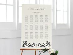 a wedding seating chart on an easel with flowers