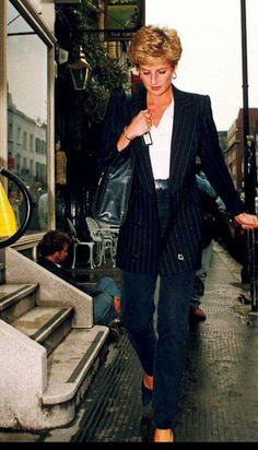 a woman is walking down the street with her hand in her pocket and holding an umbrella