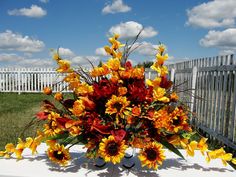 a vase filled with yellow and red flowers on top of a white table covered in grass