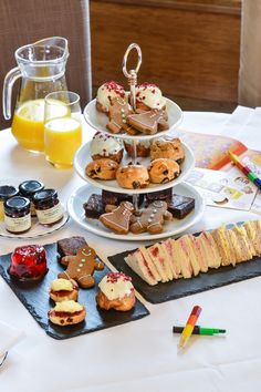 a table topped with lots of desserts and pastries next to a book filled with orange juice