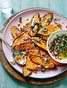 a pink plate topped with sliced up potato wedges and a bowl of salsa next to it