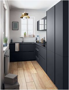 a kitchen with black cabinets and wooden floors