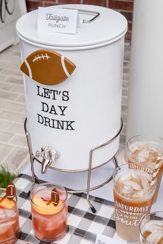 an ice bucket with drinks in it sitting on a checkered table cloth next to cups