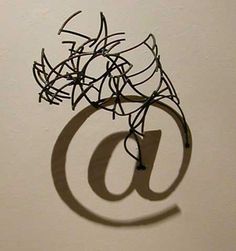 the shadow of an email sign is cast on a white wall with a black wire