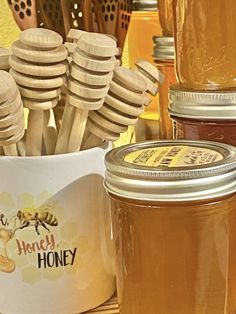 honey jars and wooden spoons are sitting next to each other