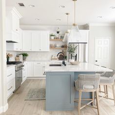 a kitchen with white cabinets and blue island in the center, surrounded by bar stools