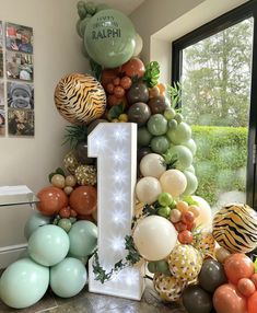 a number one surrounded by balloons and jungle animals is displayed in front of a window