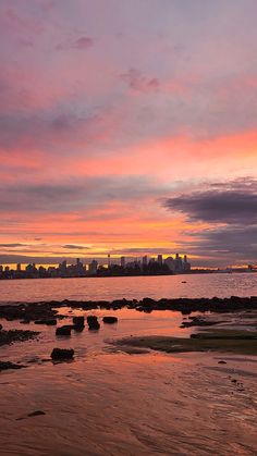 the sky is pink and orange as the sun sets over the cityscape in the distance