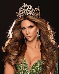 a woman with long hair wearing a tiara and green dress is posing for the camera