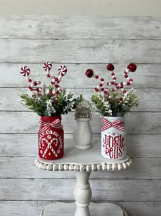 two red and white jars with candy canes in them sitting on a cake stand