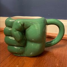 a green ceramic coffee mug sitting on top of a wooden table