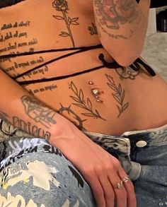 a woman with tattoos on her stomach is sitting down and holding a cell phone to her ear