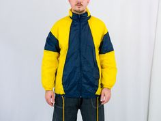 "UNCLE ED PRESENTS - vintage 90's yellow-blue windbreaker - the hood hidden in the collar - 2 outside pockets - lined - material: shell - 100% nylon; lining - 100% cotton. CONDITION (1-10 ❶❷❸❹❺❻❼❽❾ Great condition. SIZE/MEASUREMENTS size from label: M; women 40-42, men 48-50 best fits men: M/L chest: 51 inches (130 cm) length: 30 inches (76 cm) sleeve length from armpit: 18,5 inches (47 cm) The model is 6'1\" (186 cm), measures 41-35-39 (104-88-100 cm) and wears size L" Yellow Sporty Windbreaker For Outdoor Activities, Yellow Windproof Windbreaker For Outdoor, Sporty Yellow Hooded Jacket For Outdoor, Yellow Sporty Hooded Jacket For Outdoor, Sporty Yellow Hooded Jacket For Streetwear, Yellow Hooded Jacket With Pockets For Streetwear, Sporty Yellow Windbreaker For Streetwear, Yellow Sporty Windbreaker For Streetwear, 90s Style Yellow Windbreaker For Streetwear