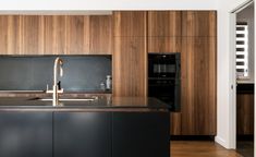 a modern kitchen with wood paneling and stainless steel appliances on the countertop, along with black cabinets