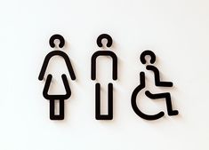 three black cut out signs on a white wall with a person sitting in a wheelchair