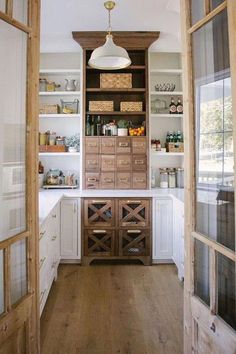 an open kitchen with lots of wooden cabinets and shelves on the wall, along with glass doors leading to another room