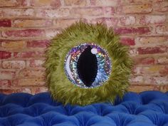 an eyeball is sitting on top of a blue cushion in front of a brick wall