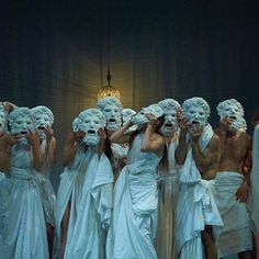 a group of people with white masks on their faces and hands in front of them